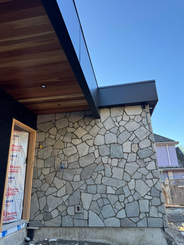 Irregular flagstone veneer wrapping the exterior wall of a modern home with cedar soffit